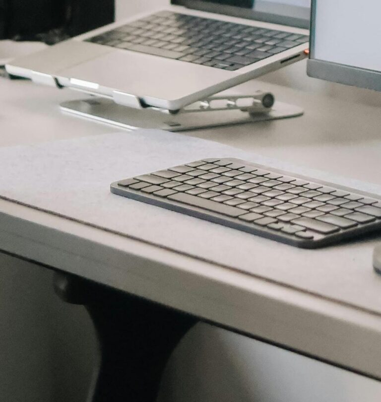 Laptop and screen on a desk with keyboard